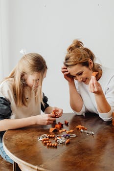 A mother and daughter enjoy crafting together at a wooden table indoors.