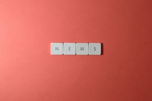 Close-up of keyboard keys spelling 'NEWS' on a red background, minimalist style.