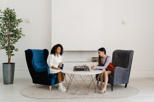 Two women engaged in a chess game in a stylish indoor setting, showcasing strategy and leisure.