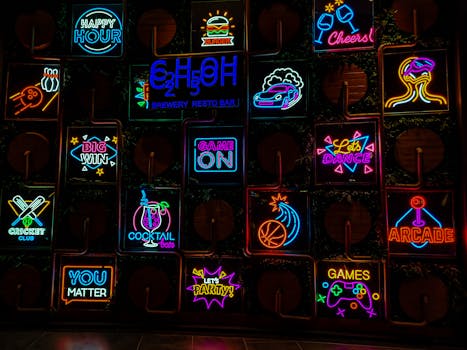 Vivid neon signs showcasing cocktails, gaming, and nightlife at a Gurugram bar.