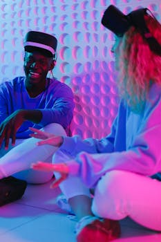 Two adults enjoying a virtual reality experience together indoors, surrounded by colorful lighting.