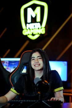 A woman smiling at a gaming setup, perfect for esports content.